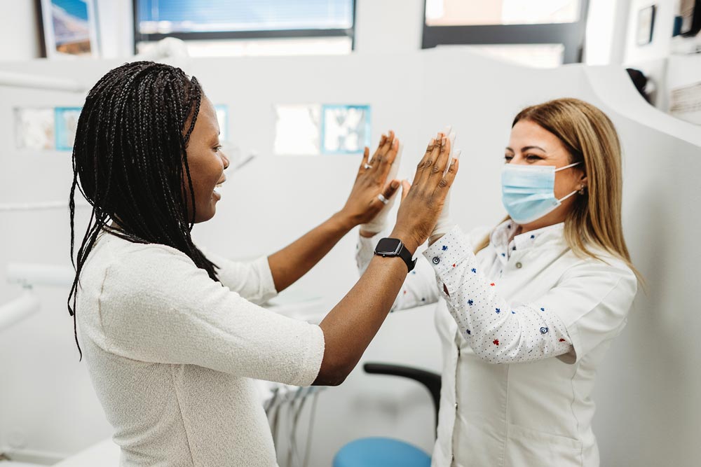 Patient med tandläkarskräck får high five från tandläkare efter lyckar besök.