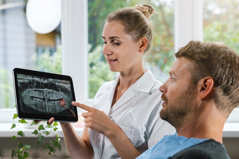 Tandläkare som visar patient röntgenbild av visdomstand